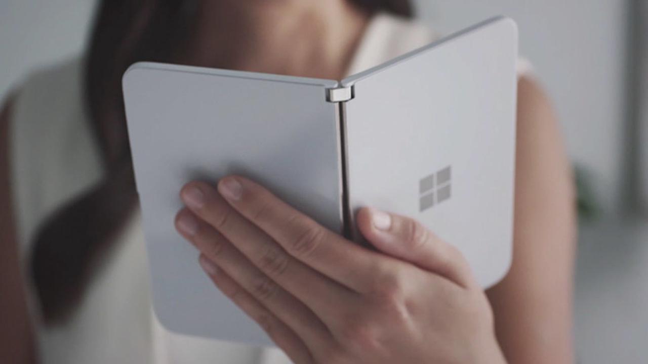 A woman holding white Microsoft surface duo on her palm