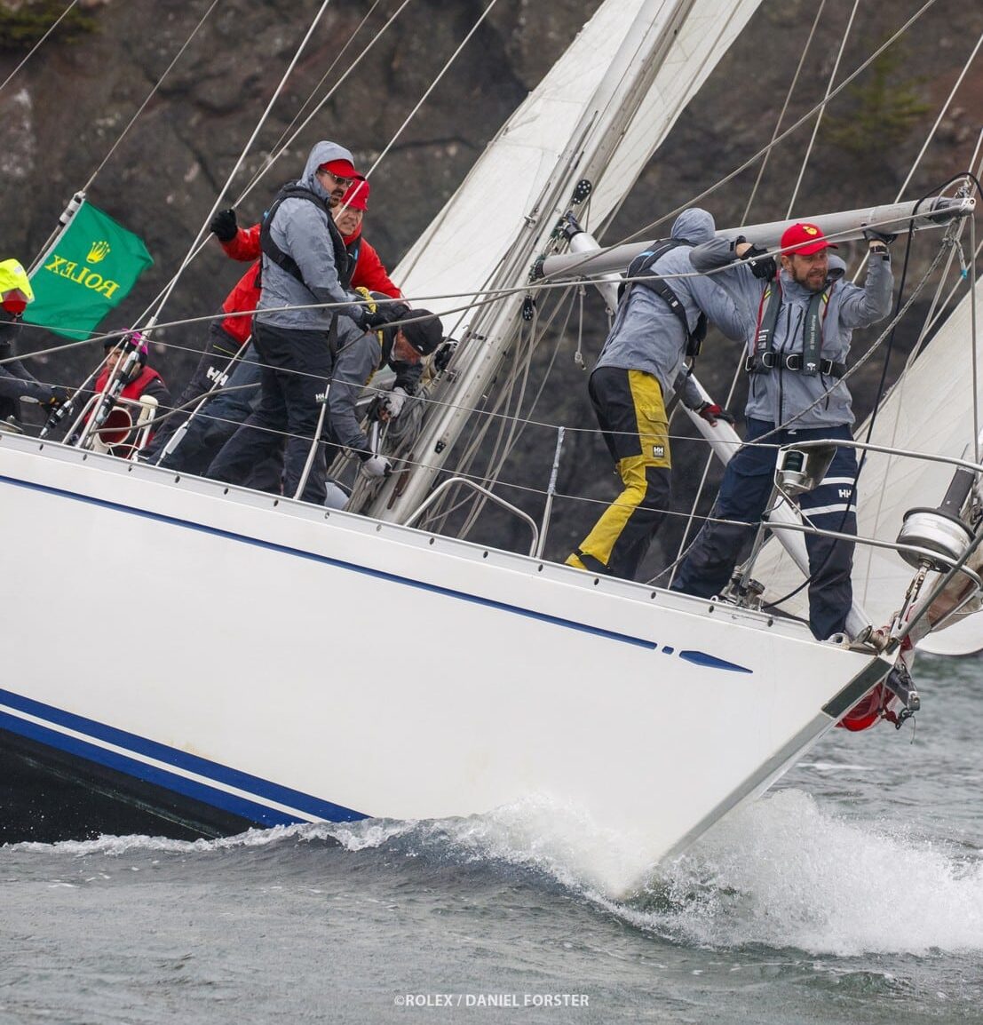 Typon, a 1976 Swan 47, sailing upwind under the Marin headlands during the 2026 Rolex Big Boat Series, with crew working on the foredeck and a Rolex flag flying from the stern.